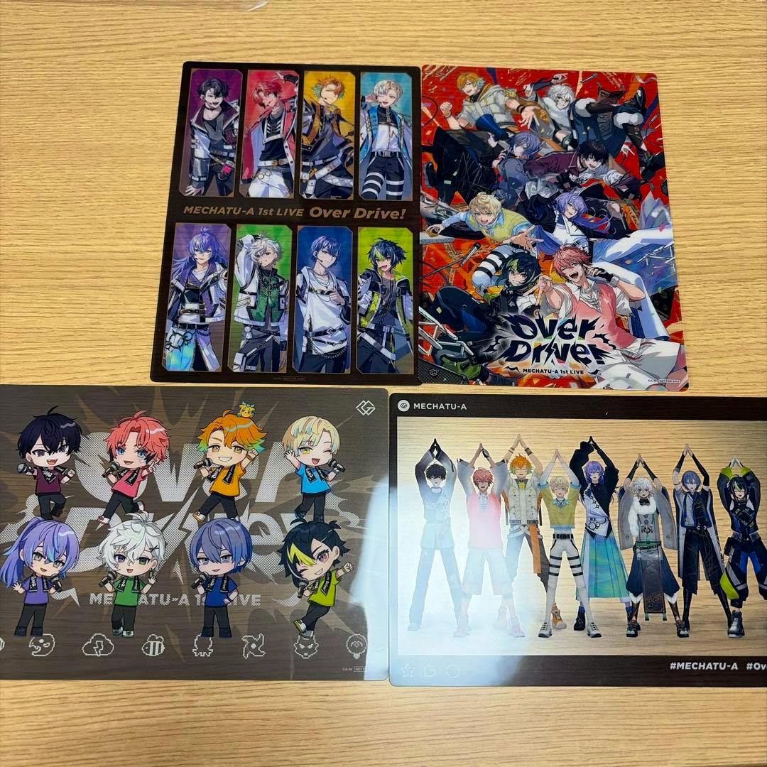 Four MECHATU-A visual photocard designs laid out on a wooden table showing illustrated characters and chibi-style designs.