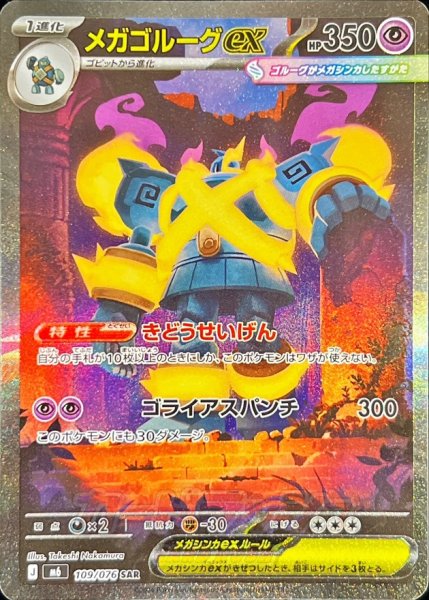 Photograph of the trading card メガゴルーグex showing the holographic front with full-art illustration and Japanese text.
