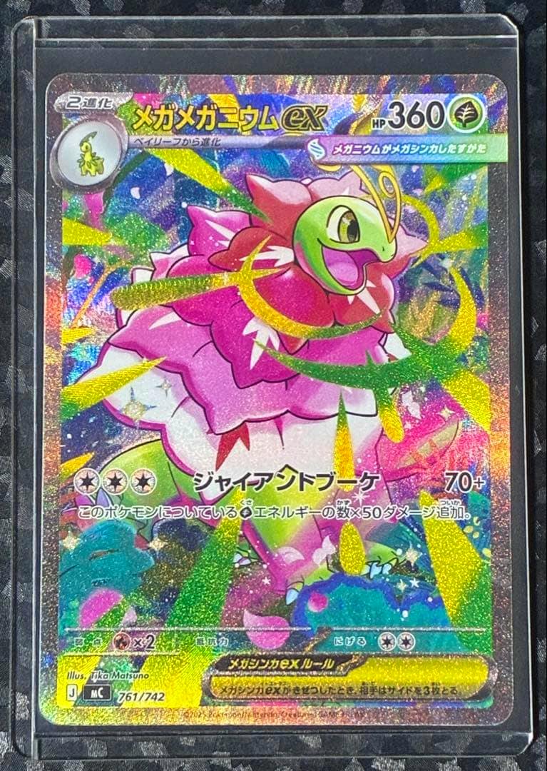 Close-up photo of the holographic メガメガニウム ex Pokémon trading card (card number 761/742) shown in a clear protective sleeve.