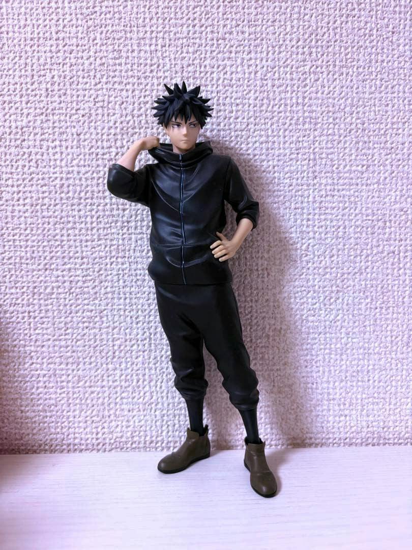 Plastic figure of Fushiguro Megumi from Jujutsu Kaisen standing against a textured wall, wearing a black jacket and pants.