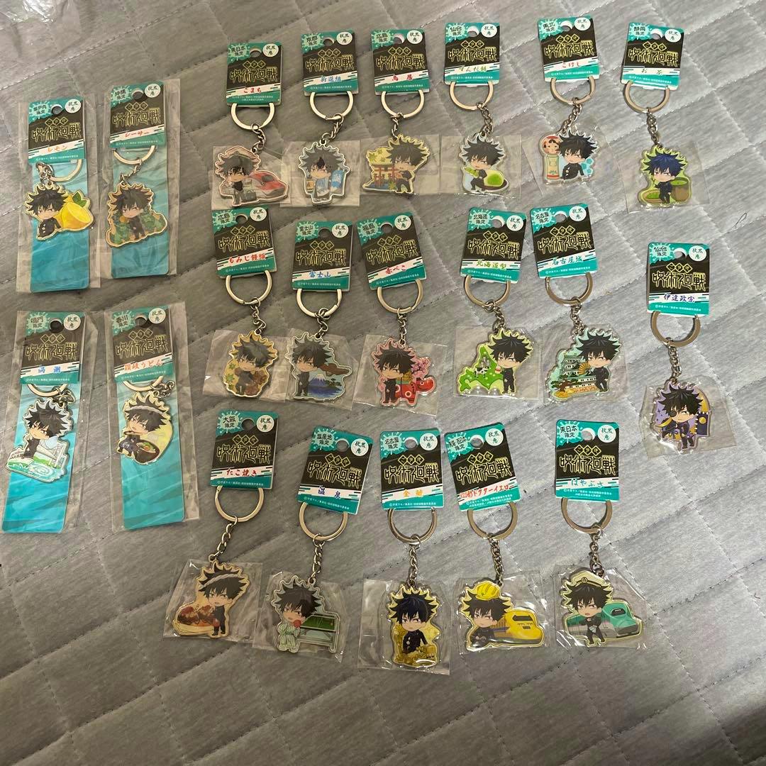 Photo showing Megumi Fushiguro Jujutsu Kaisen metal keychains (bag charms) arranged on a gray quilted surface.