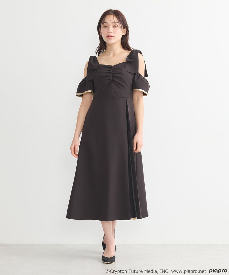 A model wearing the black women's dress standing against a plain white background.