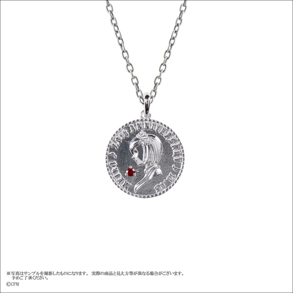Round metal coin pendant on a chain featuring a side-profile portrait and a small red gemstone.