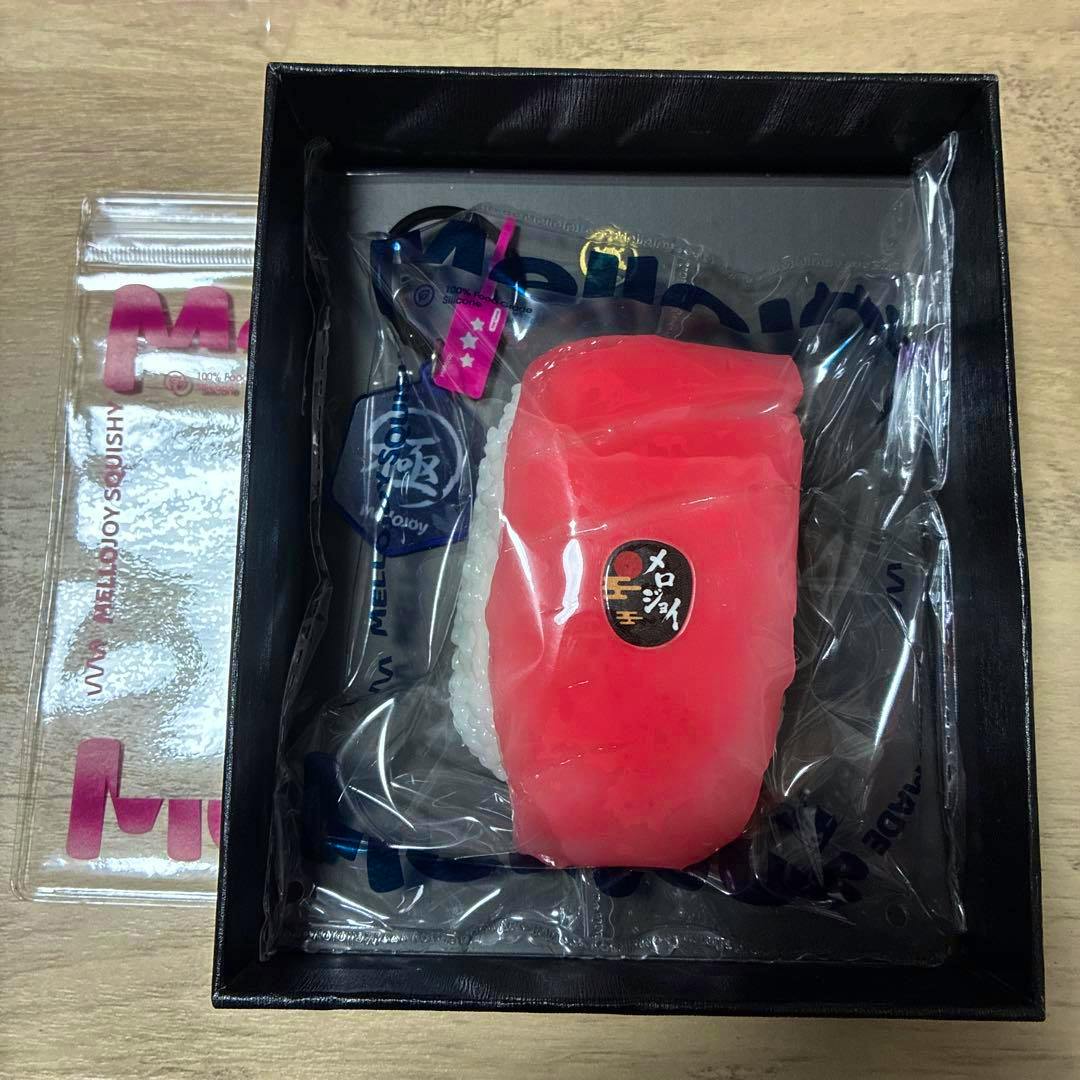A Mellojoy tuna (中トロ) sushi squishy toy in plastic packaging inside a black presentation box.