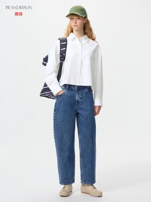 Full-length front view of a model wearing baggy blue jeans and a white shirt.