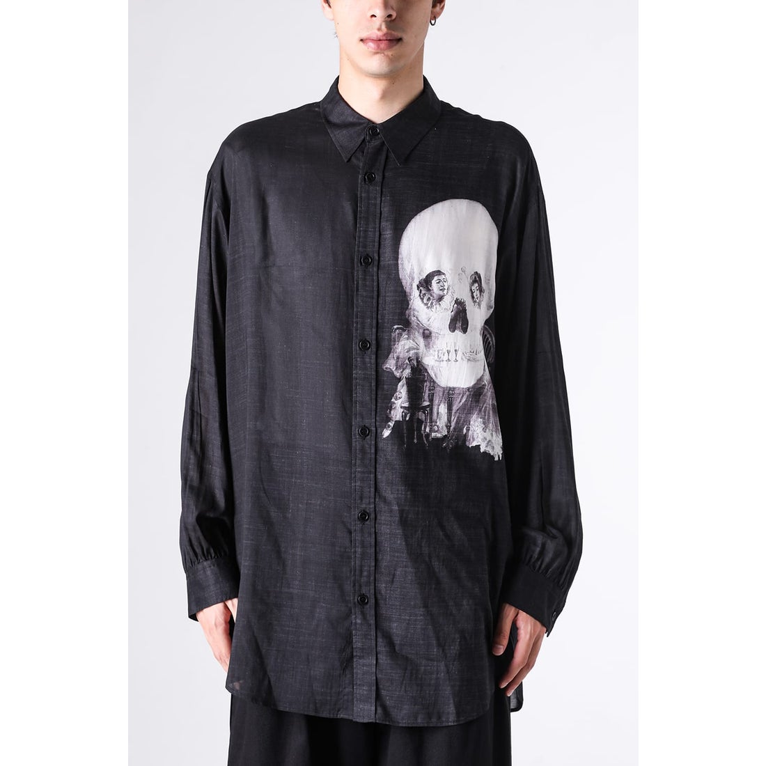 Black men's printed polyester button-up shirt with a large white skull print shown on a model from the front.