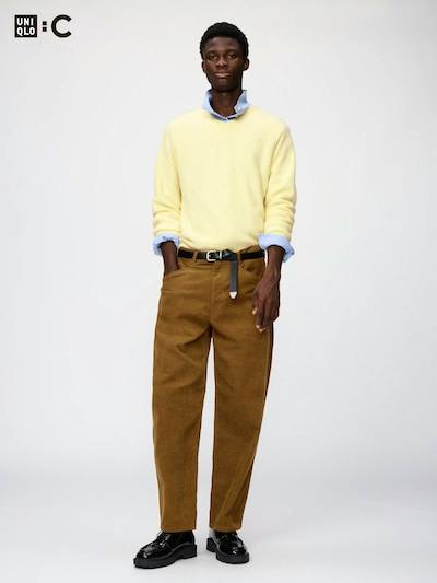 Male model standing and wearing brown corduroy men's jeans against a plain background.