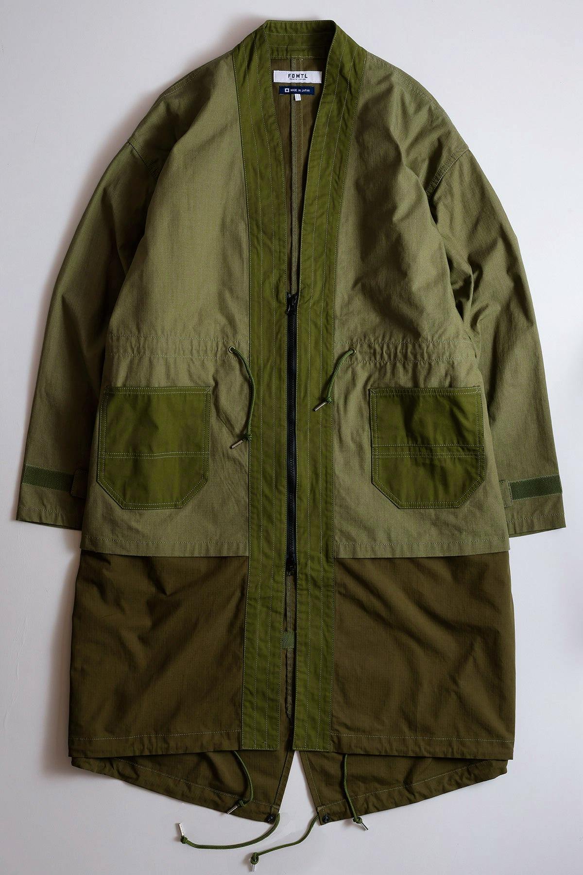 Front view of an olive-green men's cotton haori coat laid flat showing patch pockets, a central zipper, and drawcords.