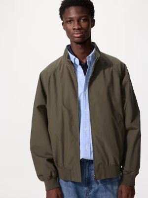Male model wearing a men's Harrington jacket in olive green over a light blue shirt.