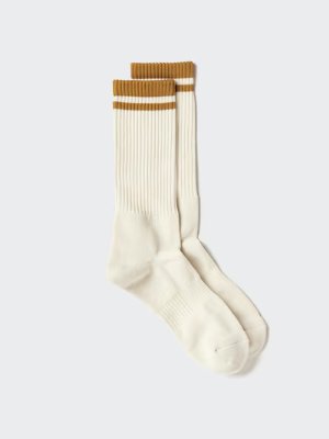 A pair of cream-colored sports socks with mustard double stripes at the cuffs laid flat on a light background.