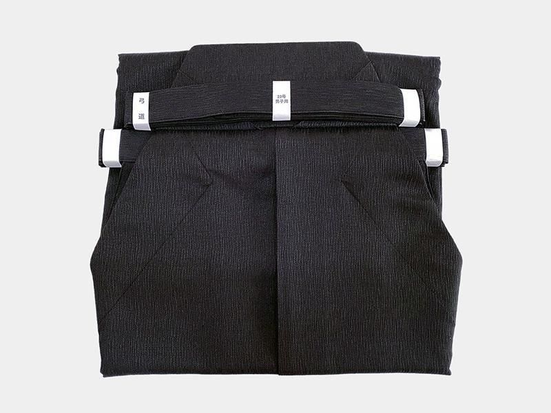Folded black hakama garment displayed on a white background.
