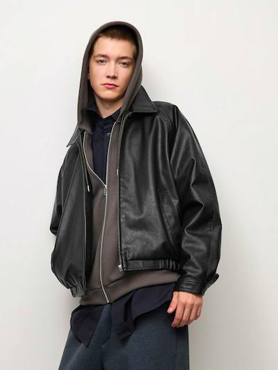 A male model wearing the black faux leather zip blouson jacket shown from the front.