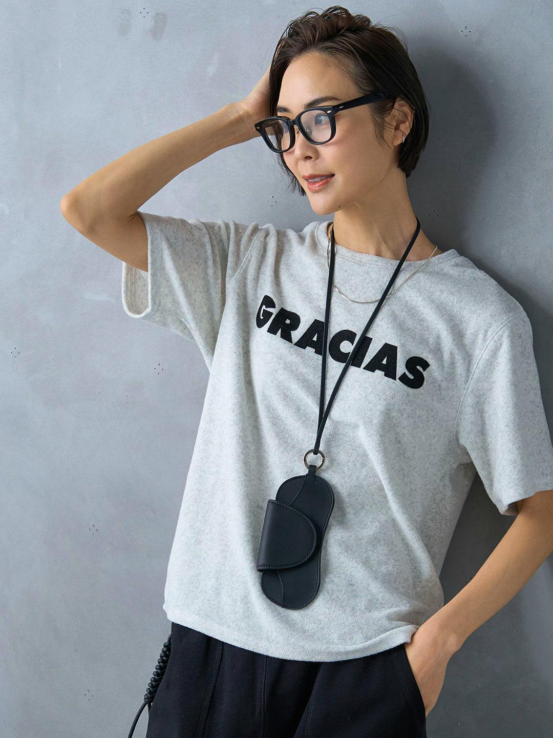 Model wearing a light gray pile T-shirt with the word "GRACIAS" printed across the chest.