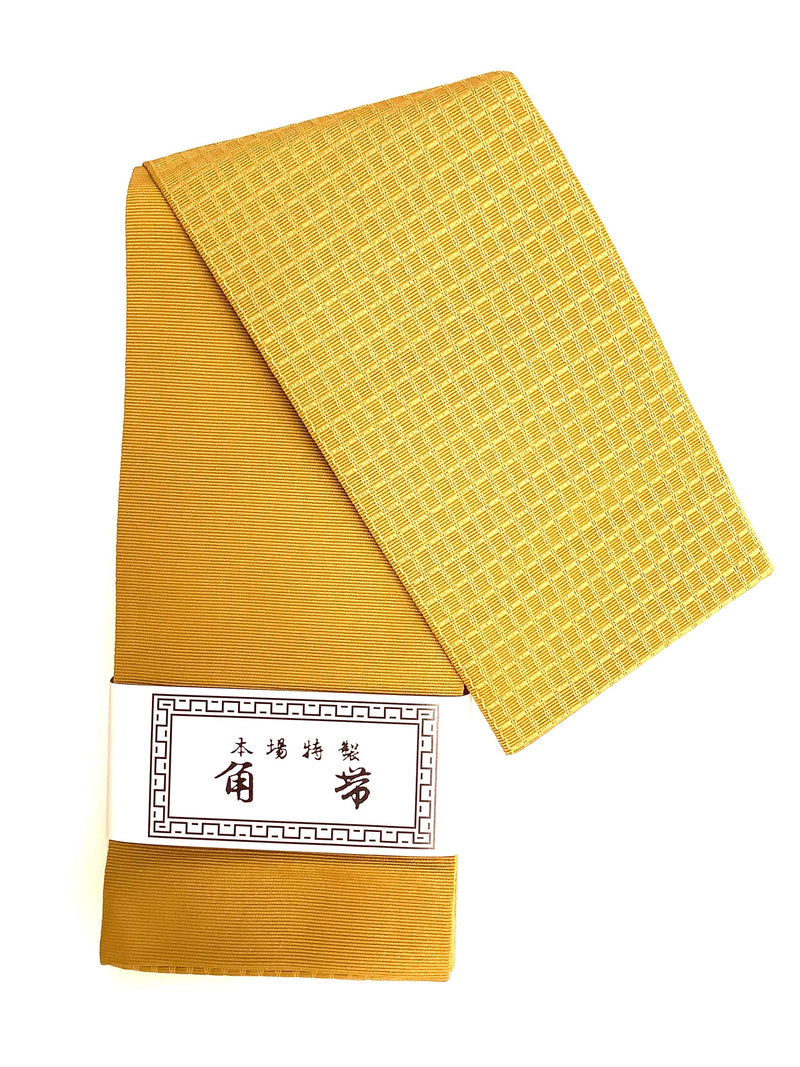 Folded men's kaku obi in gold with a textured patterned end and a paper label.