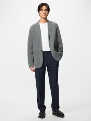 A male model standing wearing the men's pants with a blazer and T-shirt against a white background.