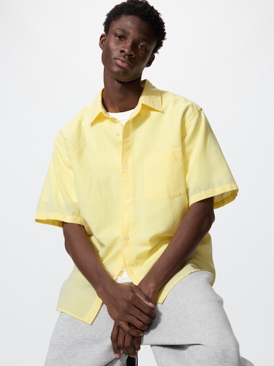 Male model wearing a yellow boxy short-sleeve men's cotton shirt against a white background.