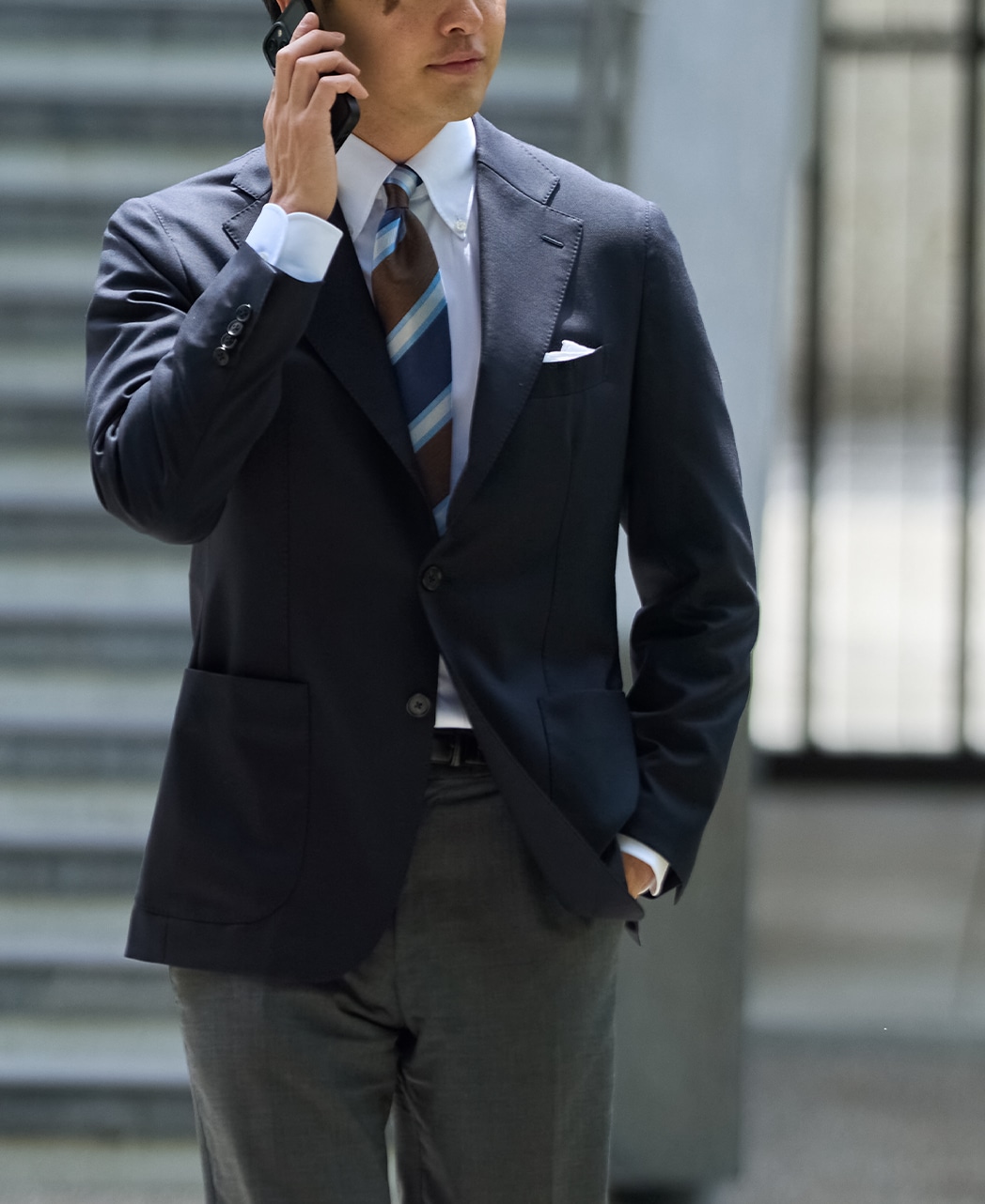 A man wearing the navy wool men's jacket (Royal Oxfords) standing and talking on a phone.