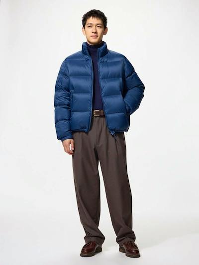 Male model wearing the men's tuck relaxed wide pants, shown full-length styled with a blue puffer jacket.
