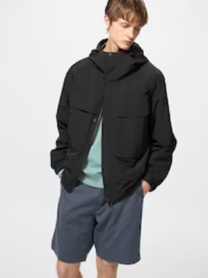 A male model wearing a black windproof parka with a hood and front pockets.