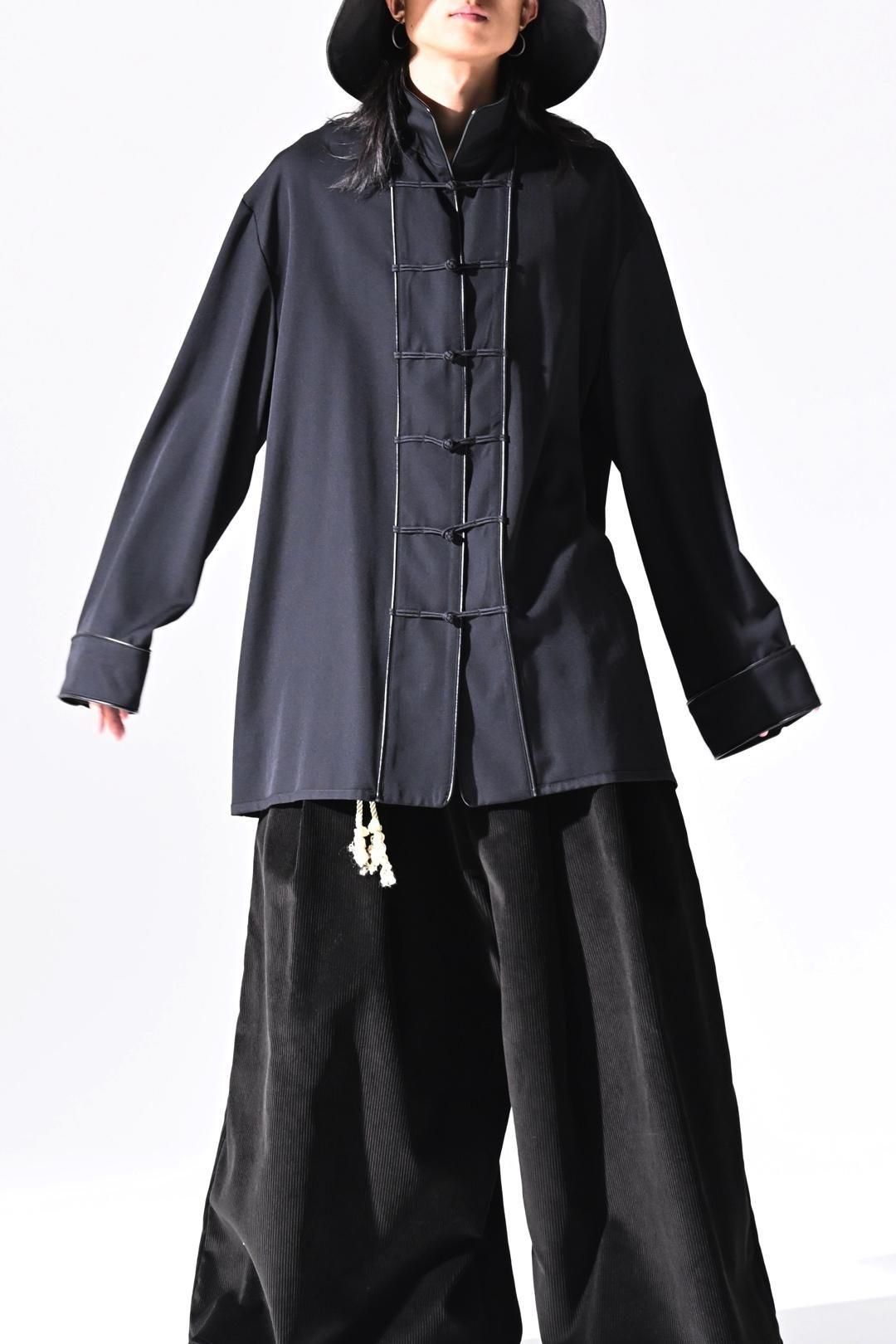 Front view of a model wearing a wool gabardine China jacket with leather piping and front toggle closures.