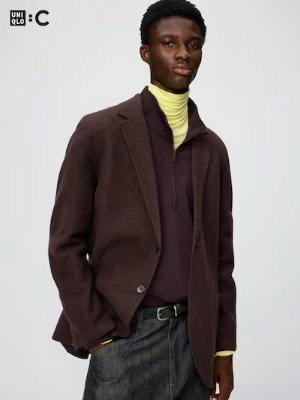 Male model wearing the men's brown knit jacket layered over a turtleneck and zip-top with dark trousers against a plain light background.
