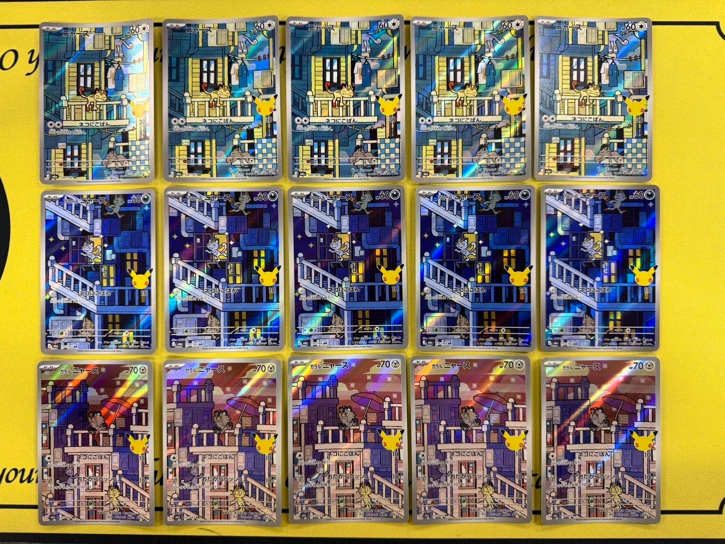 A set of Pokémon ニャース (Meowth) trading cards arranged in rows on a yellow background.