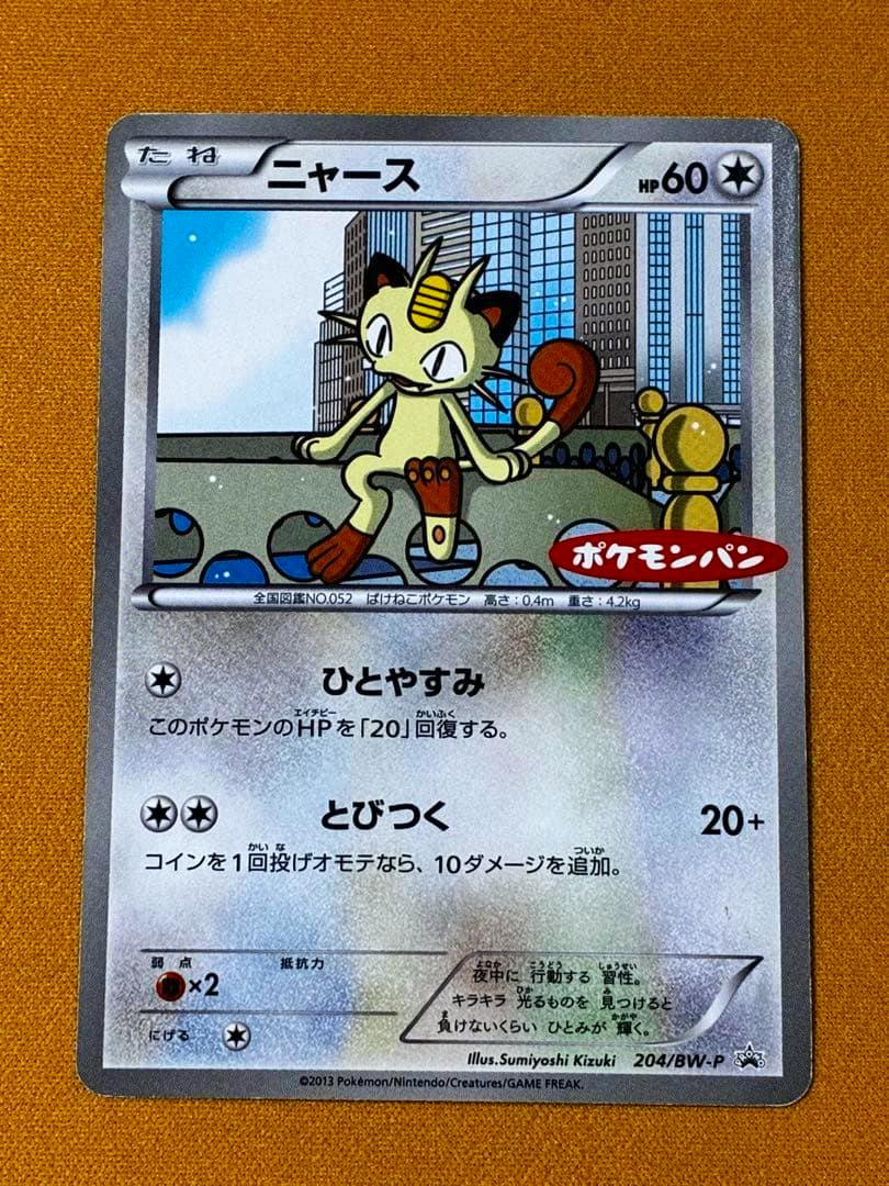 Front of the ニャース ポケモンパン プロモ 204/BW-P trading card showing Meowth artwork and Japanese text on an orange background.