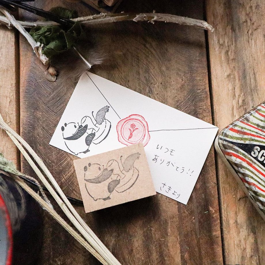 A wooden animal stamp on a wooden surface beside an envelope showing the stamped design.