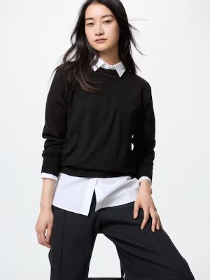 Woman wearing a black merino crew-neck sweater layered over a white button-up shirt.