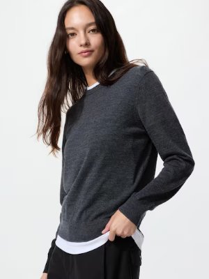 Model wearing a dark gray merino crew neck sweater in a three-quarter pose.