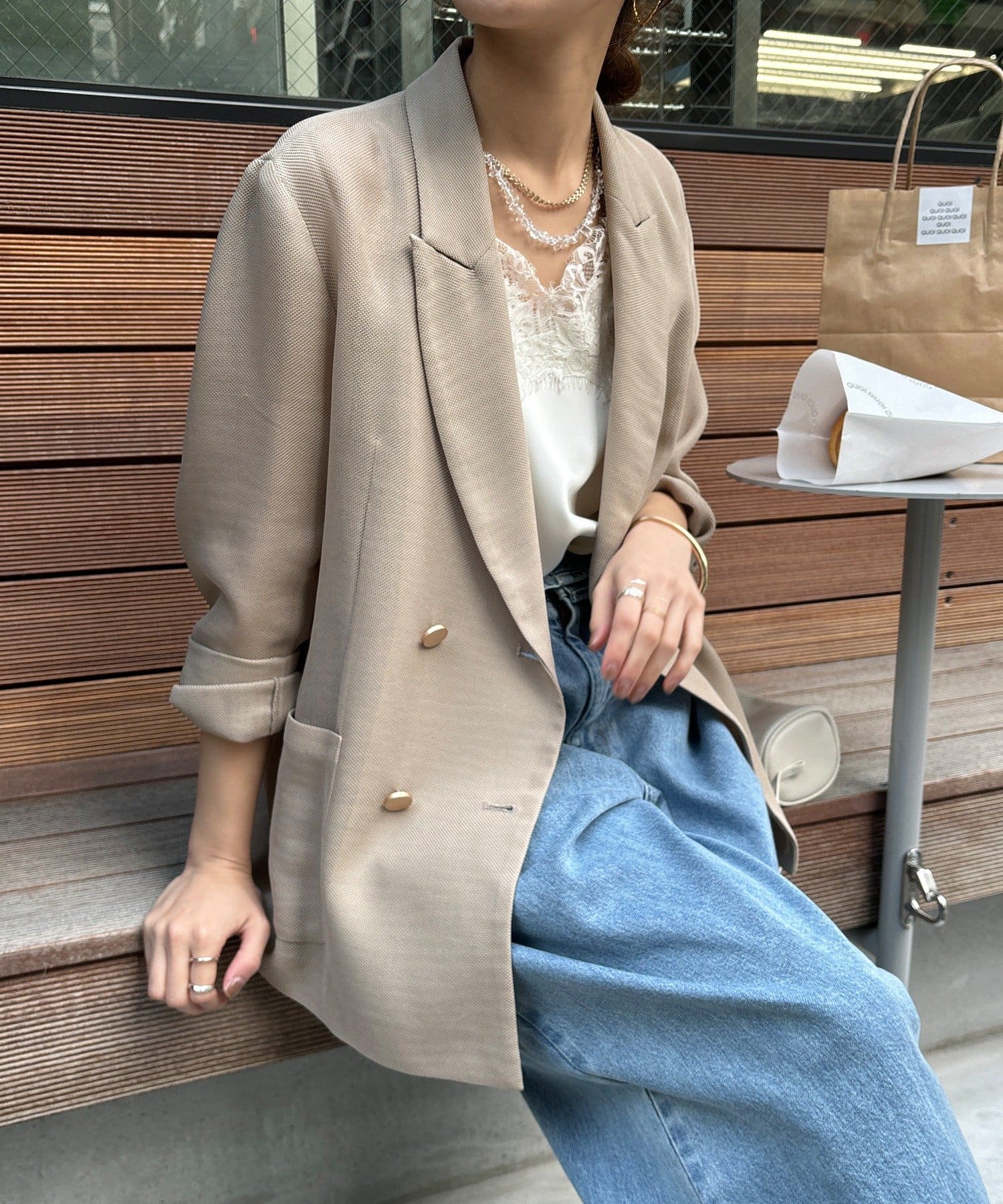 Model seated wearing the women's mesh double jacket (rayon) in beige with rolled sleeves over a lace camisole and blue jeans.