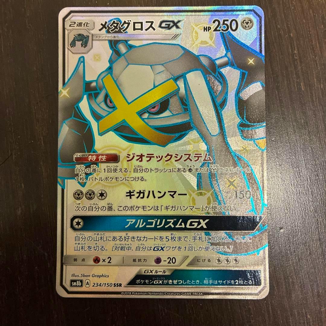 Front of a Metagross-GX Pokémon trading card in Japanese with holographic foil, photographed on a dark wood surface.