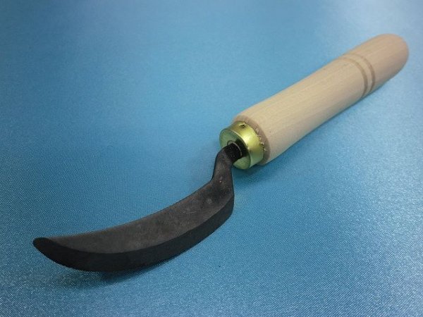Curved metal file with a wooden handle placed on a blue surface.