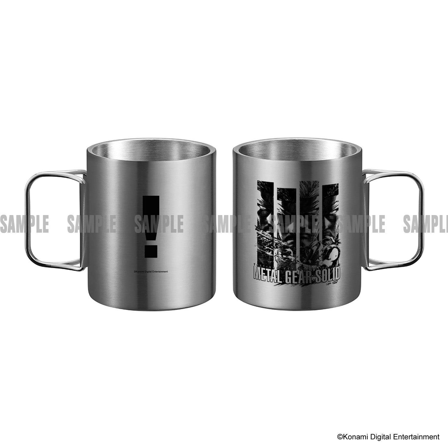 Two stainless steel METAL GEAR SOLID mugs shown side by side, one with an exclamation mark and the other with character artwork and the "METAL GEAR SOLID" logo.