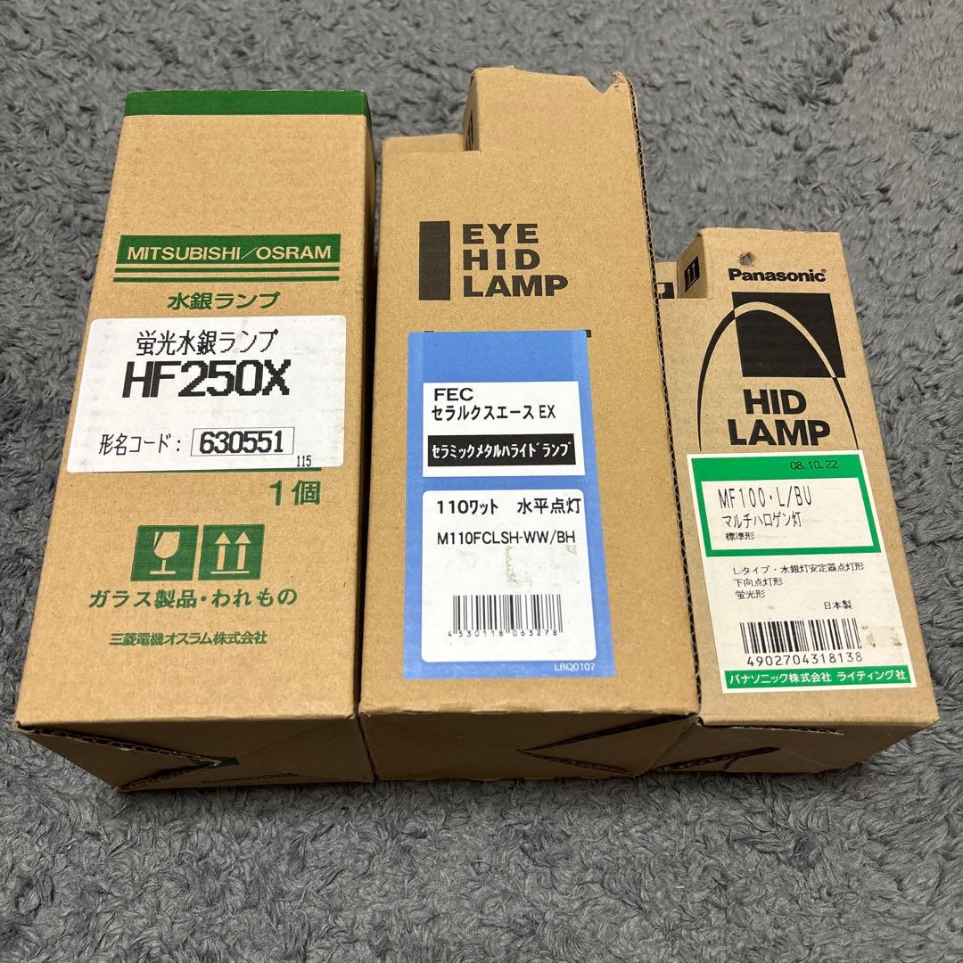 Three boxed HID light bulbs from different manufacturers shown side by side on a carpeted surface.
