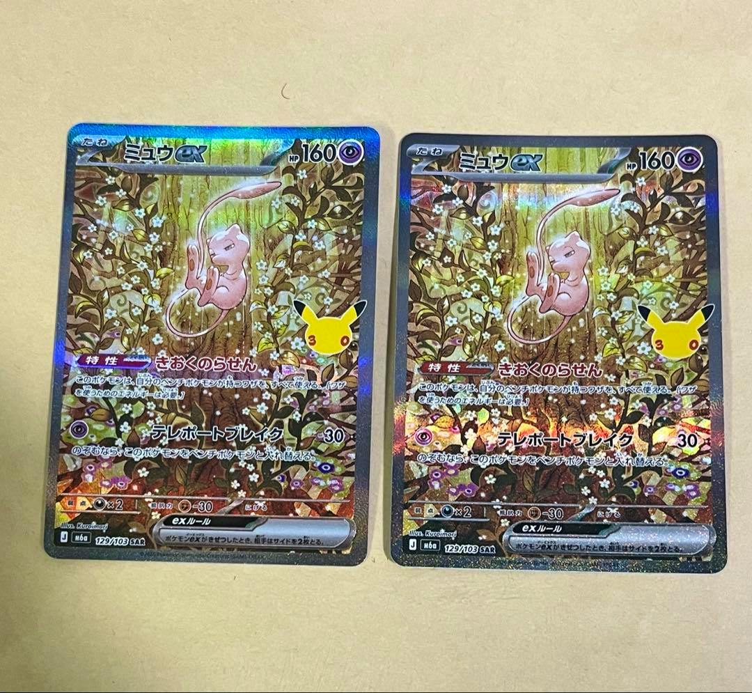 Two Mew ex SAR trading cards (129/103) shown side by side on a beige surface.
