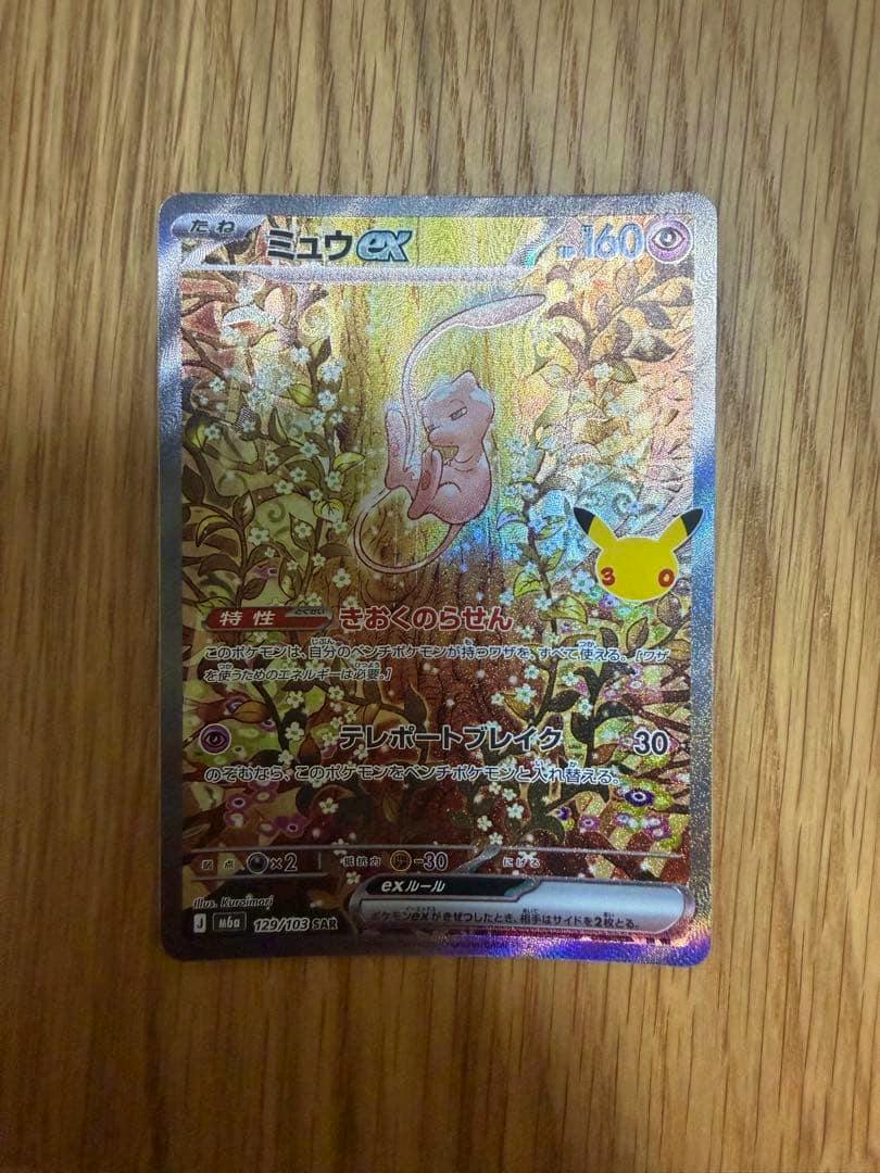 Photograph of the ミュウex trading card placed on a wooden surface, showing the full card face.