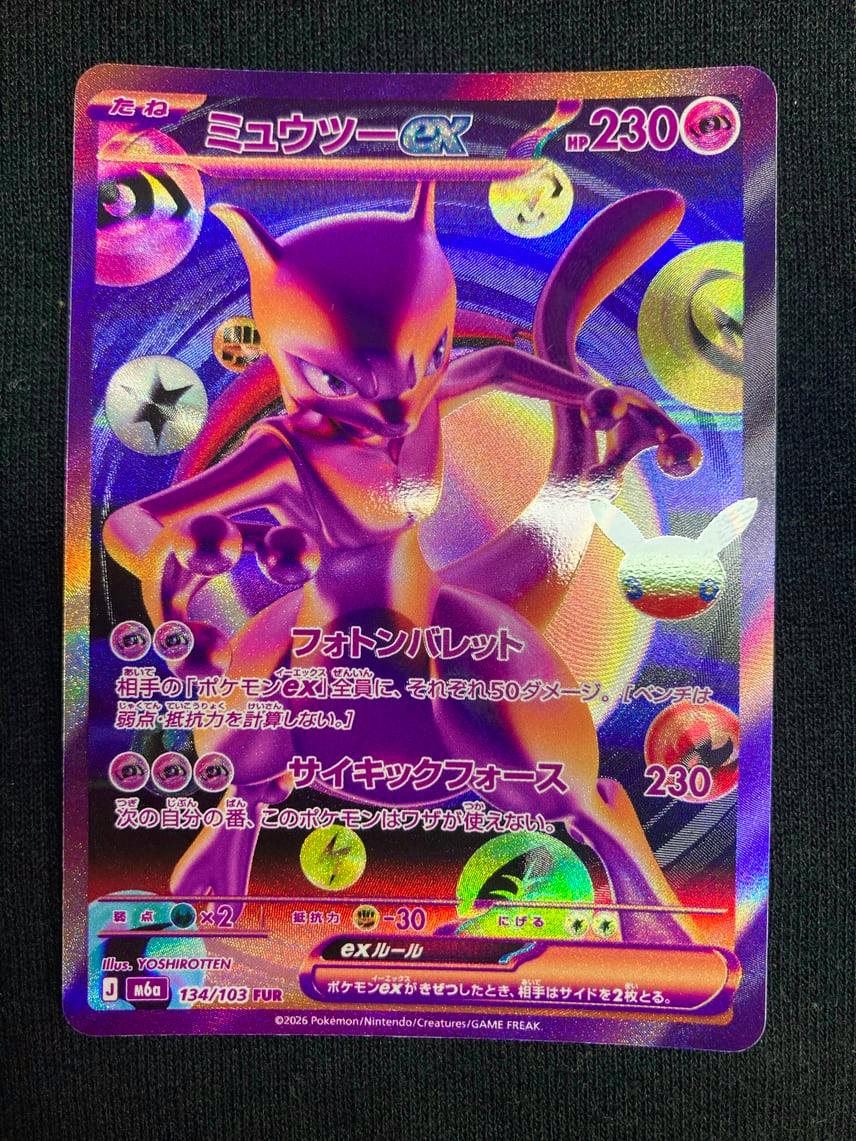 Front of the holographic ミュウツーex trading card (M6a 134/103) from the 30th CELEBRATION expansion on a dark fabric background.
