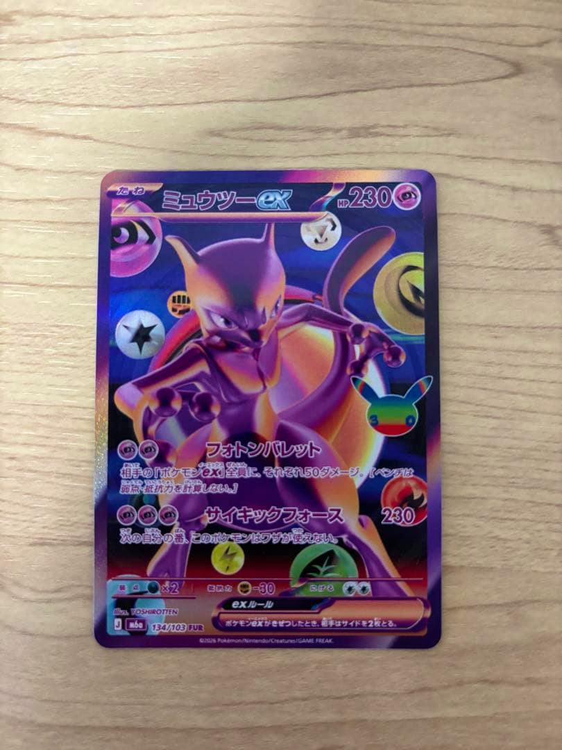 Front view photograph of the ミュウツーex (Mewtwo ex) trading card with holographic foil on a light wood background.