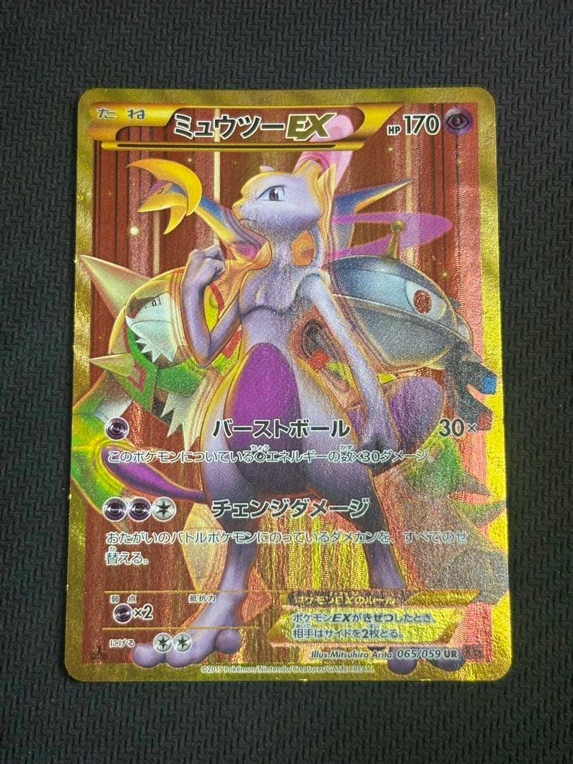 Photo of the ミュウツーEX UR XY8 赤い閃光 065/059 trading card placed on a black textured surface.