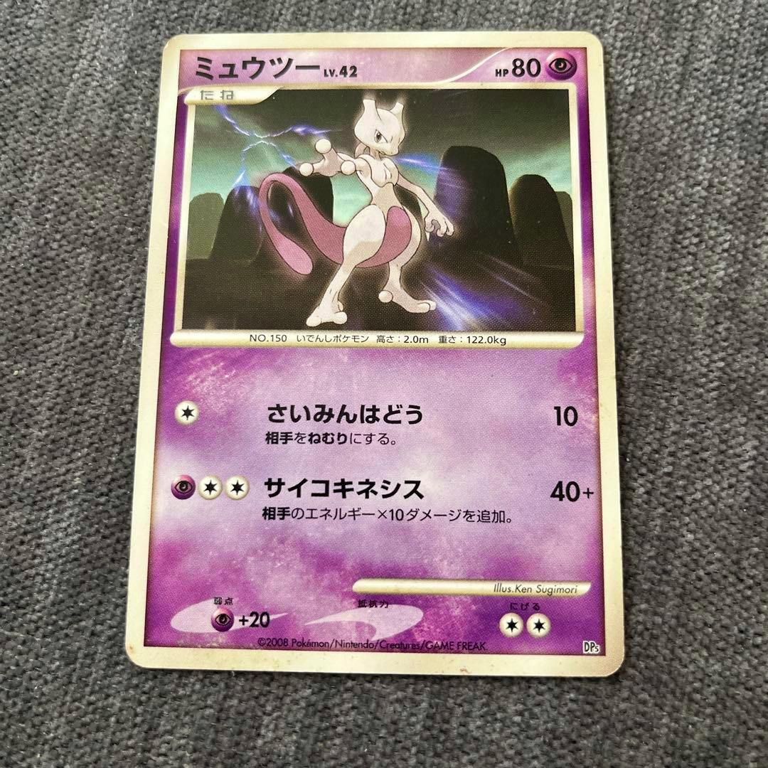 Top-down photo of the ミュウツー LV.42 trading card showing the card artwork and Japanese text on a gray fabric background.
