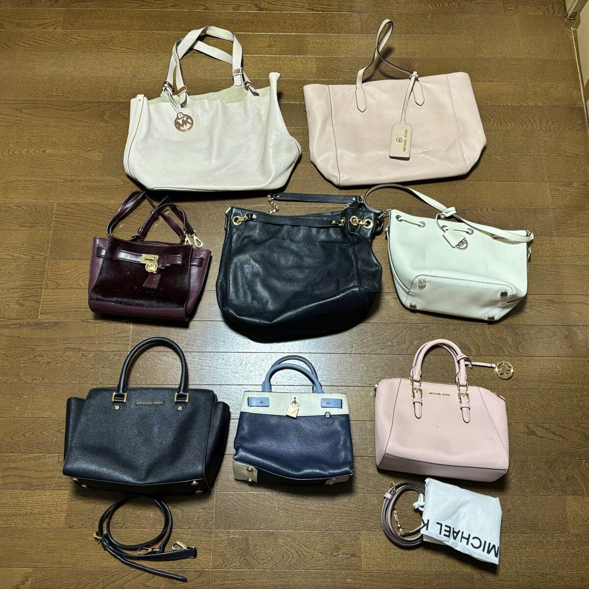 A set of Michael Kors bags (8-piece lot) of various styles and colors arranged on a wooden floor.
