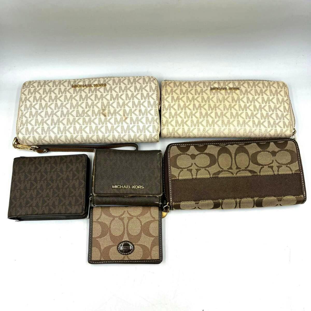 Multiple wallets and card holders including Michael Kors and Coach monogram patterns arranged on a white background.