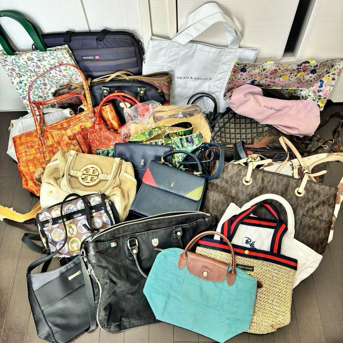 A large assortment of various handbags and tote bags laid out on a floor.