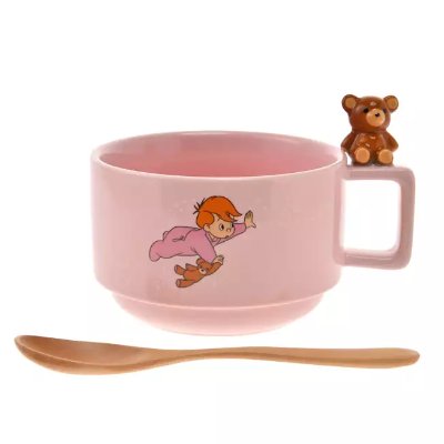 Pink ceramic soup cup with a small teddy bear figurine on the handle and a matching spoon placed in front.
