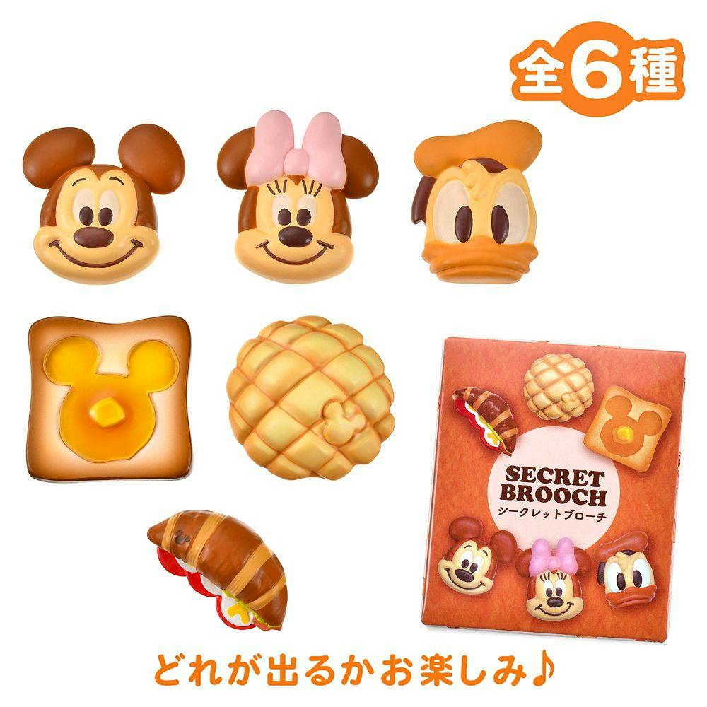 Mickey, Minnie, and Donald bakery-themed secret brooches alongside the product box on a white background.