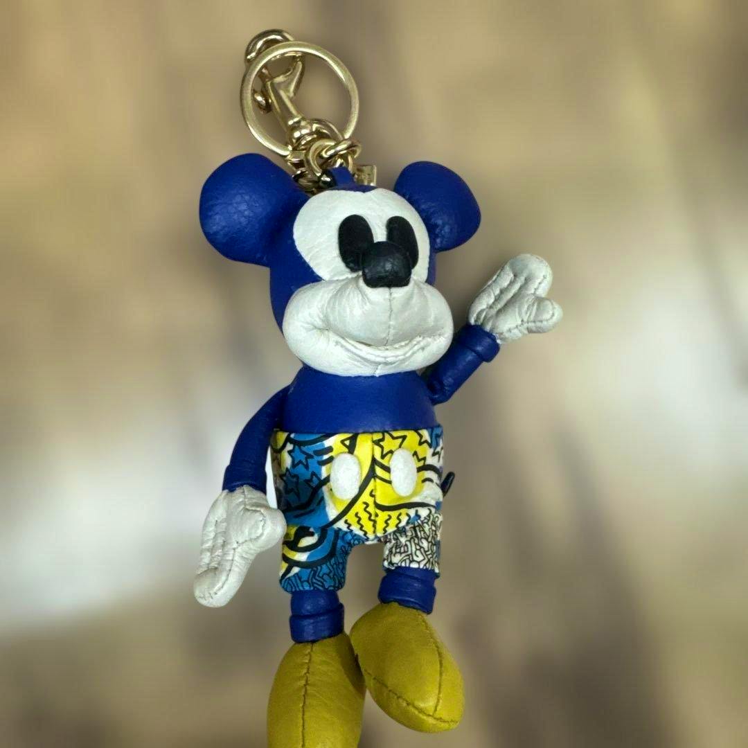 Mickey Mouse x Keith Haring cow leather charm with a blue body, patterned shorts, yellow shoes, and a gold keyring.