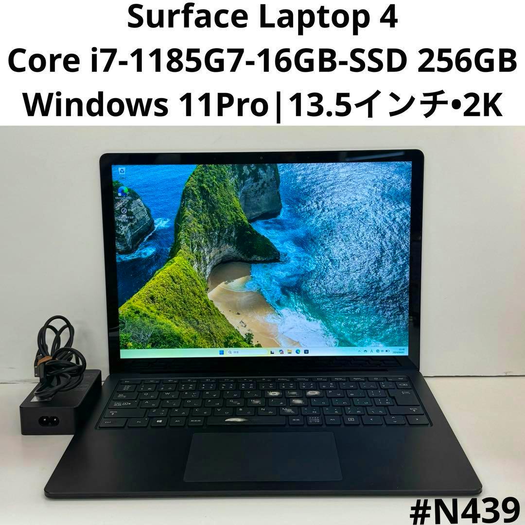 Front view of the Surface Laptop 4 with its screen on, keyboard visible, and power adapter to the left.