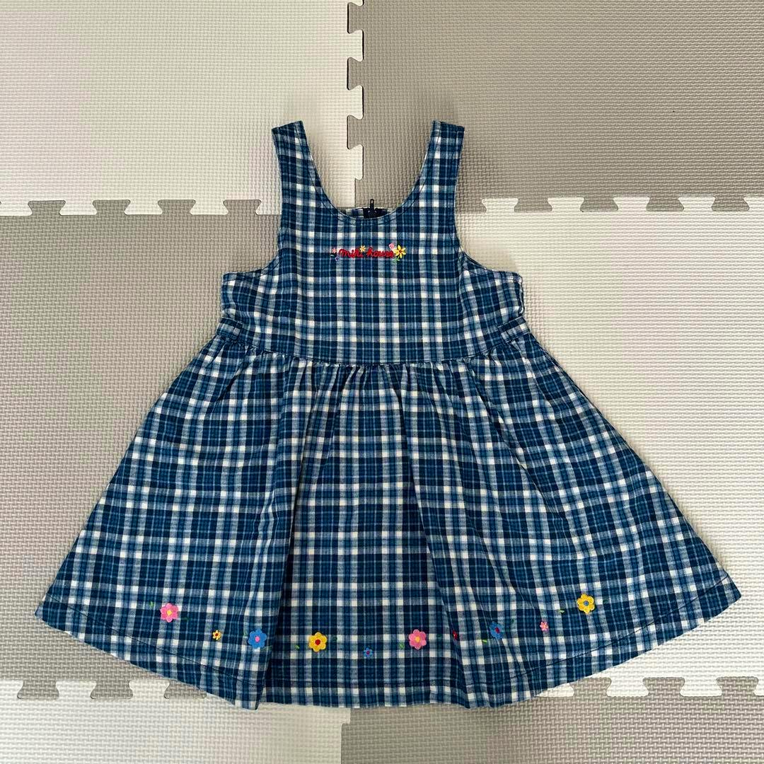 Blue and white checked jumper skirt with small flower embroidery laid flat.