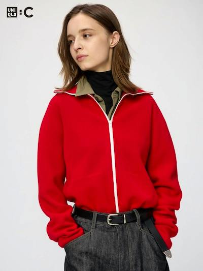 Model wearing a red Milano-rib full-zip cardigan with white trim and dark trousers.